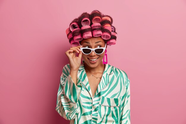 Portrait of pleasant looking young wearing hair curlers and casual silk dressing gown