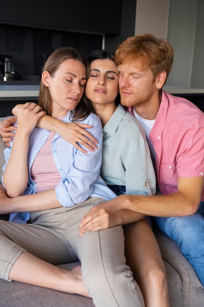 Portrait of polyamorous couple at home sitting on the couch together