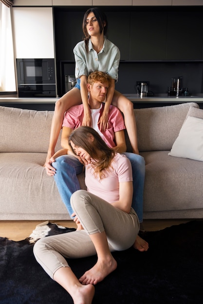 Free photo portrait of polyamorous couple at home sitting on the couch together