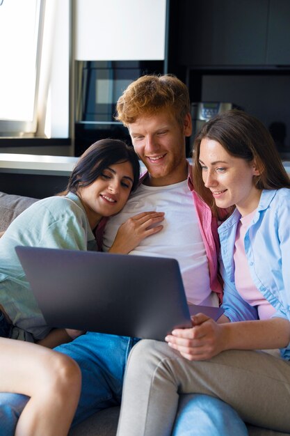 Portrait of polyamorous couple at home sitting on the couch and using laptop