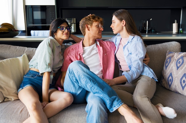 Portrait of polyamorous couple at home sitting on the couch