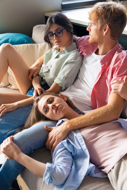 Portrait of polyamorous couple at home sitting on the couch
