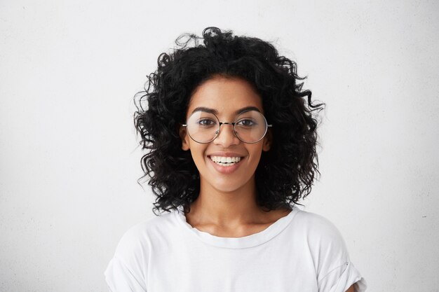 Portrait of positive carefree dark-skinned girl dressed casually smiling broadly