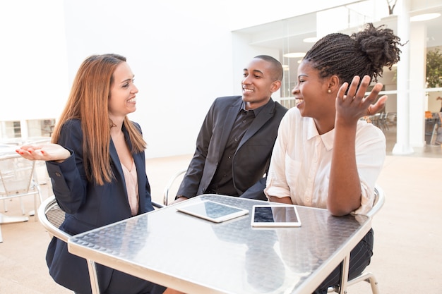 Portrait of positive colleagues laughing and talking in cafe