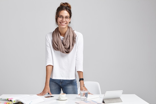 Portrait of positive female student prepares for classes, reads scientific literature