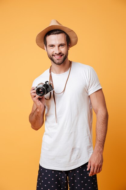 Portrait of positive man with retro camera standing isolated