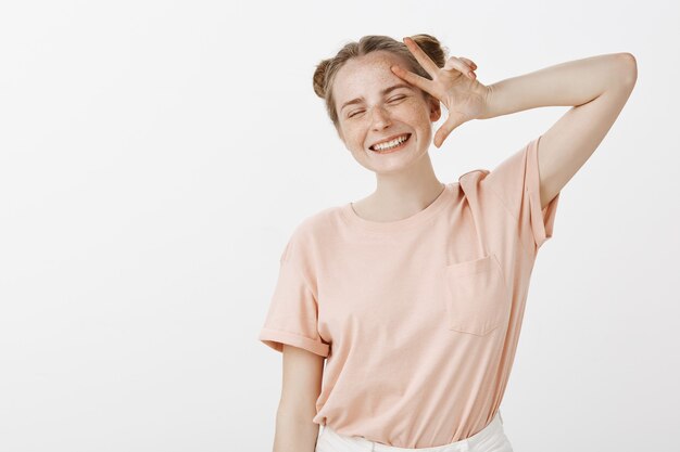 Portrait of positive teenage girl posing against the white wall