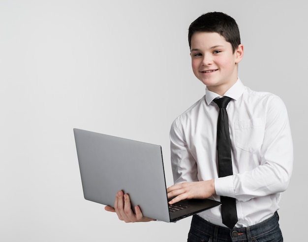 Free photo portrait of positive young boy holding laptop