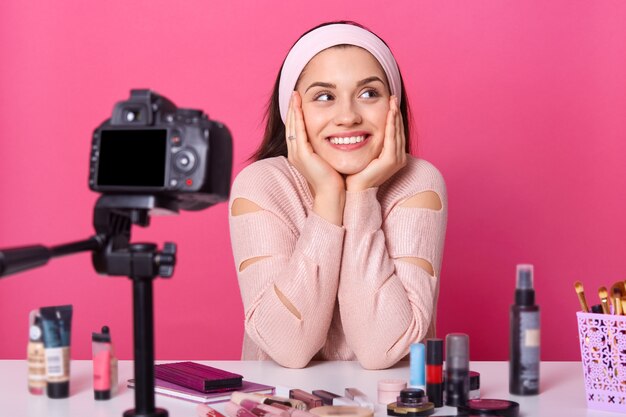 Portrait of positive young female blogger filming video for her blog