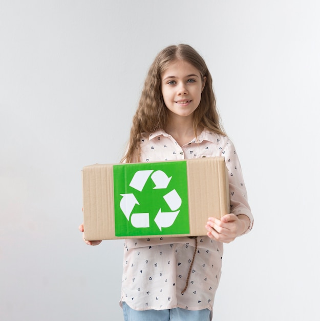 Portrait of positive young girl holding recycling box