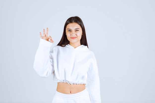 Portrait of a positive young girl showing ok gesture.