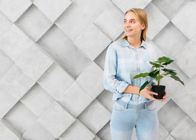 Portrait of positive young woman holding a plant