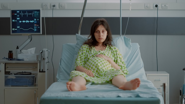 Free photo portrait of pregnant person sitting in hospital ward bed