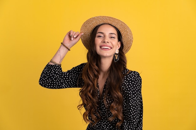 Portrait of pretty attractive woman posing isolated on yellow background wearing black dotted dress and straw hat