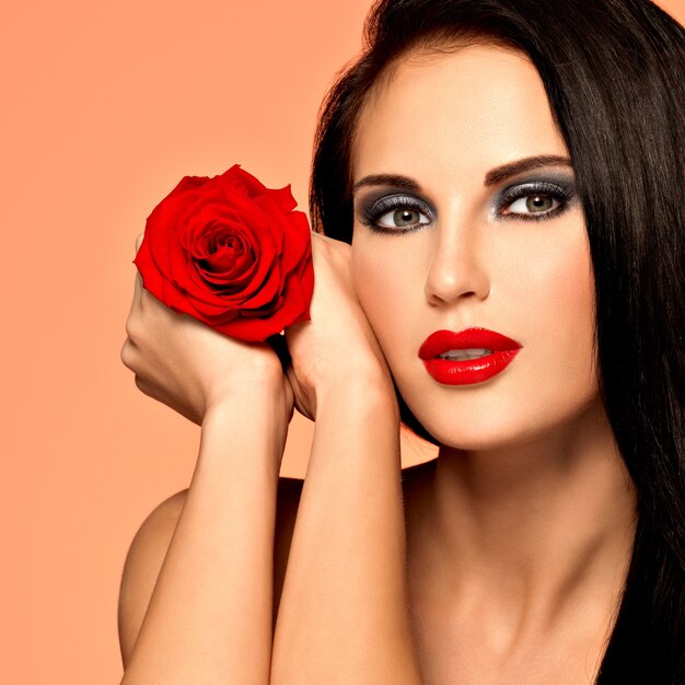 Portrait of  the pretty  beautiful woman with  bright fashion makeup holds red rose