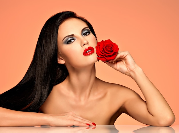 밝은 패션 메이크업으로 예쁜 아름다운 여자의 초상화는 빨간 장미를 보유