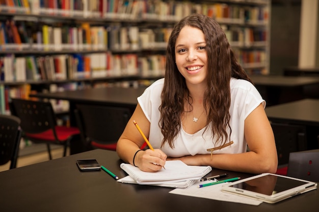 Portrait of a pretty brunette with curly hair doing some homework at school and smiling