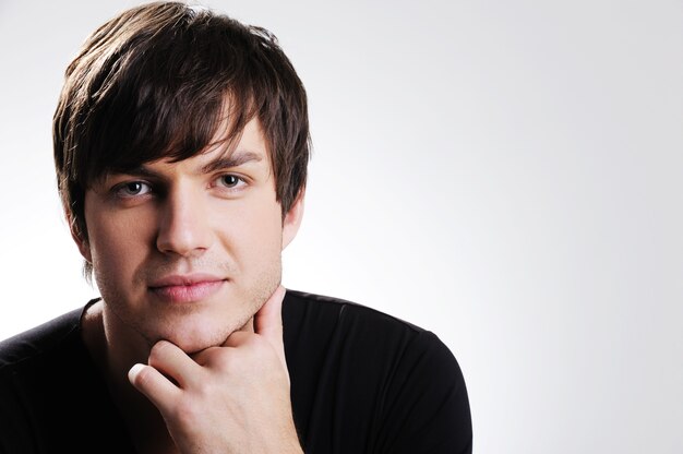 Portrait of a pretty caucasian young guy with hand at his chin