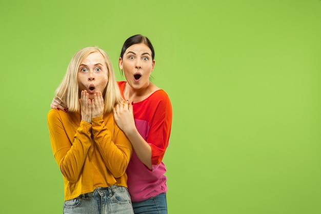 Portrait of pretty charming girls in casual outfits on green studio