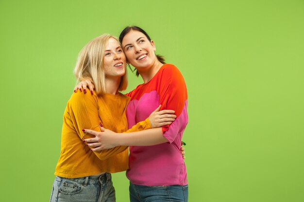 Portrait of pretty charming girls in casual outfits isolated on green studio wall