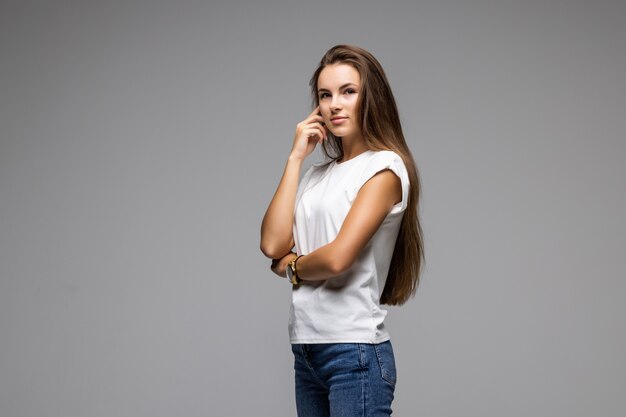 Portrait of pretty confident thoughtful girl, holding hand near the face, looking seriously up, standing over grey