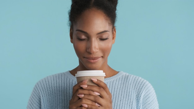 Portrait of pretty cute african american girl dreamily delighting of coffee smell on camera over colorful background