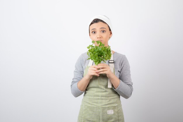 Portrait of a pretty cute woman holding beam of fresh parsley 