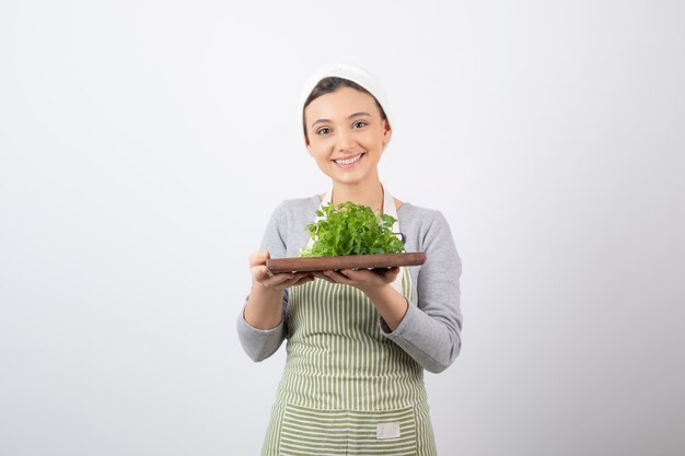 Portrait of a pretty cute woman holding a wooden board with fresh parsley