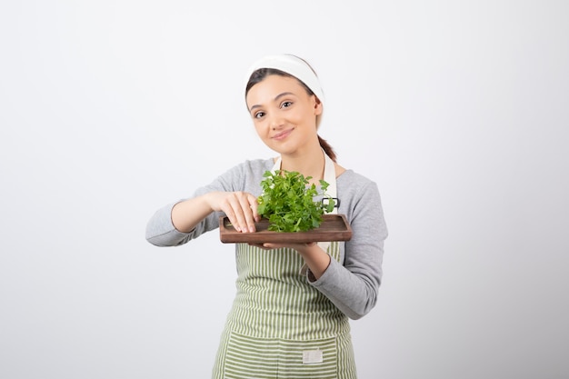 Portrait of a pretty cute woman holding a wooden board with fresh parsley