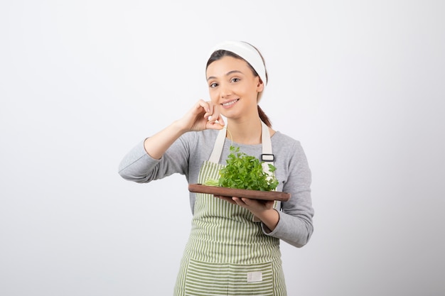 Portrait of a pretty cute woman holding a wooden board with fresh parsley