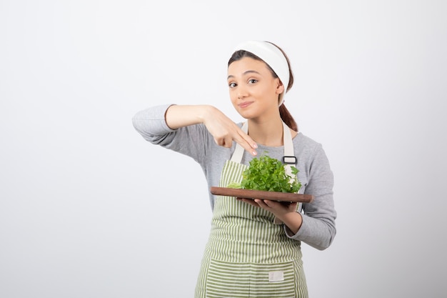 Portrait of a pretty cute woman holding a wooden board with fresh parsley