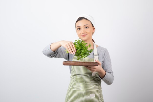 Portrait of a pretty cute woman holding a wooden board with fresh parsley