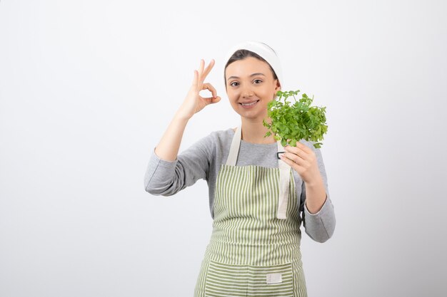 Portrait of a pretty cute woman with beam of fresh parsley showing ok gesture 