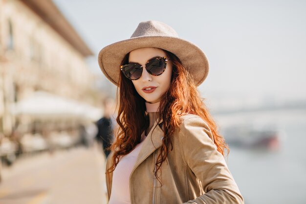 Portrait of pretty dark-haired woman with white skin standing on river wall