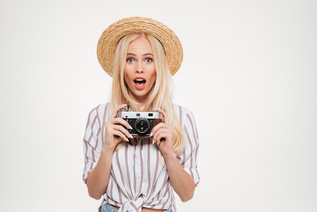 Portrait of pretty excited woman in hat holding a camera