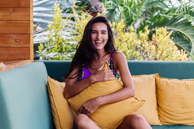 Portrait of pretty fit slim positive woman resting with pillow at home on summer outdoor sofa, enjoying time alone