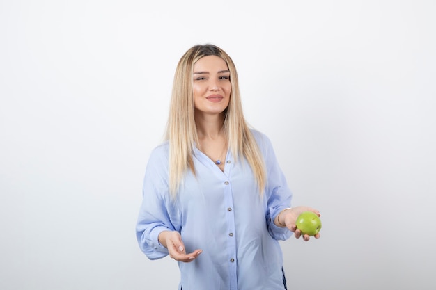 портрет красивой девушки модели стоя и держа зеленое свежее яблоко.