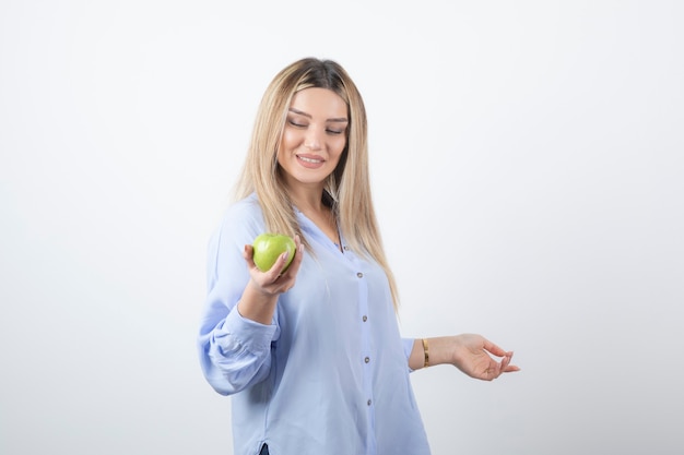 Ritratto di un modello di bella ragazza in piedi e in possesso di una mela fresca verde.