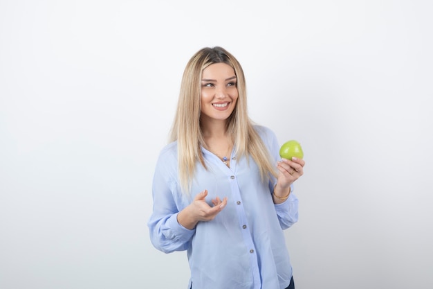 Ritratto di un modello di bella ragazza in piedi e in possesso di una mela fresca verde.