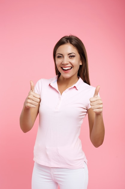 Portrait of pretty girl in pink polo showing thumb up