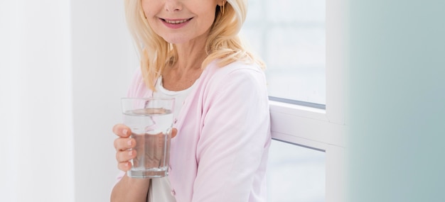 Portrait of pretty mature woman holding a glass of water