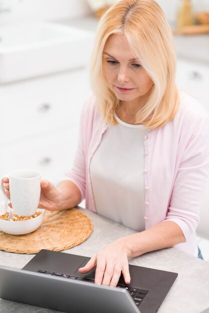 Portrait of pretty senior woman browsing a laptop