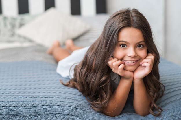 Portrait of pretty smiling girl lying on bed