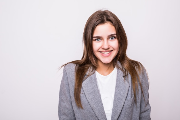 Foto gratuita ritratto di una donna sorridente graziosa che propone su una priorità bassa bianca