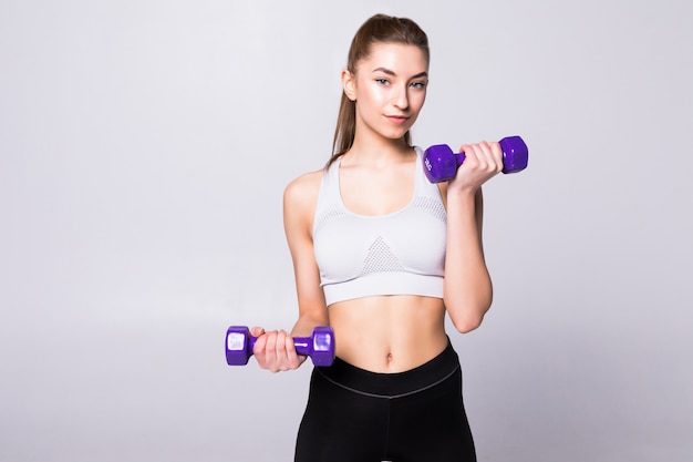 Portrait of pretty sporty woman holding weights isolated on white wall