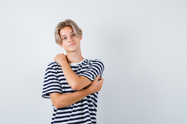 Portrait of pretty teen boy stretching arms in striped t-shirt and looking thoughtful front view