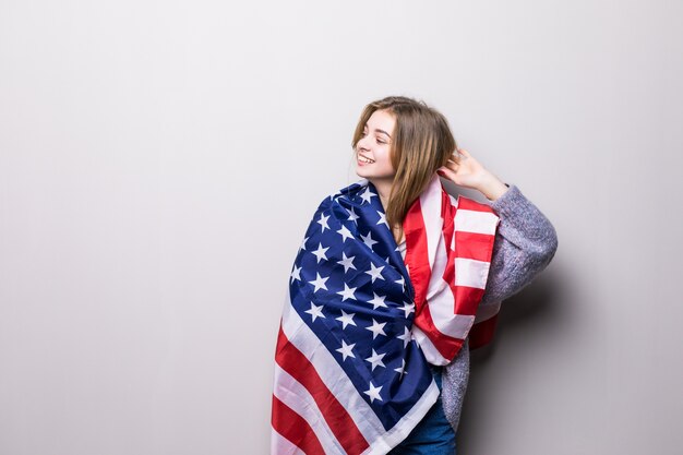 Portrait of pretty teen girl holding USA flag isolated on gray. 4th July celebration.