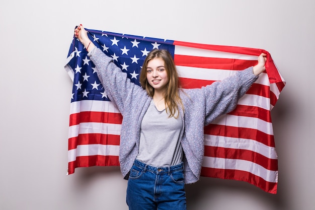 Portrait of pretty teen girl holding USA flag isolated on gray. 4th July celebration.