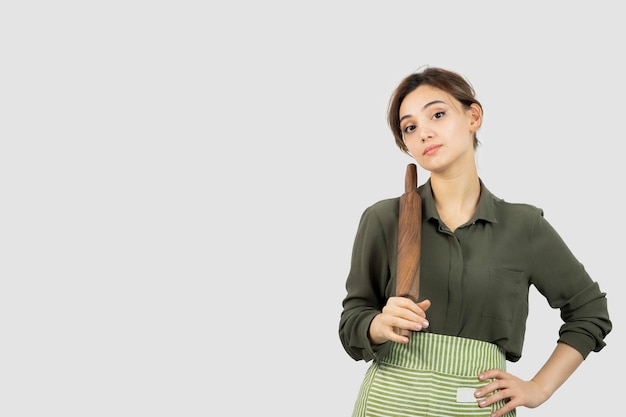 Free photo portrait of pretty woman in apron holding a rolling pin . high quality photo