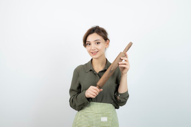 Portrait of pretty woman in apron holding a rolling pin . High quality photo